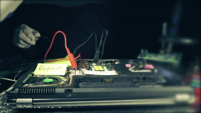 Repairman  cleaning the old laptop from dust.