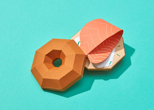 Handmade origami from paper - fish burger with peace of salmon on a turquoise background.
