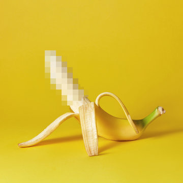Natural ripe open banana as a symbol of the penis on a yellow background, place for text.