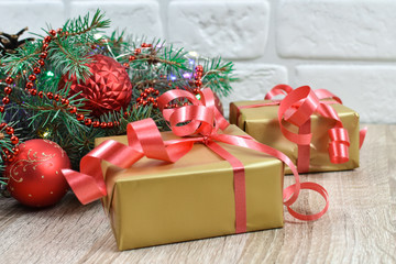Gifts near the Christmas tree on a wooden background. Red balls on the Christmas tree.