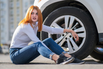 Fototapeta na wymiar Young woman with wrench waiting for help to change wheel on a broken car.