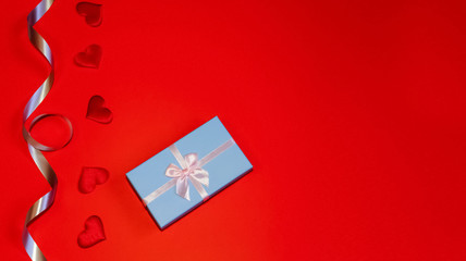 Beautiful present box with ribbon on red background with hearts. Valentine's Day festive concept. Flat lay style. Space for text