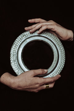 Anonymous hands holding a round mirror
