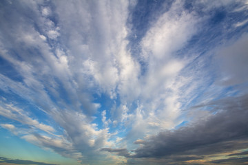 Blue sunset sky covered with white puffy clouds.