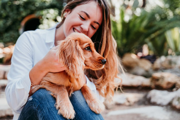 young woman and her cute puppy of cocker spaniel outdoors