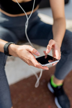 Closeup of young athlete girl preparing playlist music in her phone to run