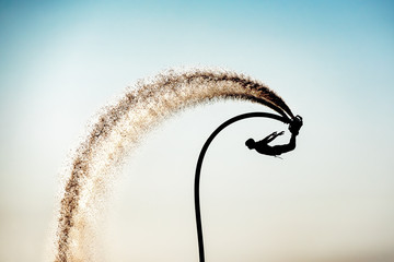 Silhouette image of a man showing the fly board (Aqua board) at sea ; The new spectacular sport