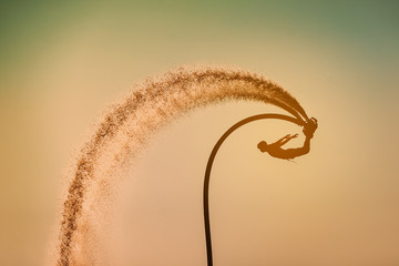 Silhouette image of a man showing the fly board (Aqua board) at sea ; The new spectacular sport