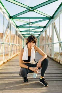 Portrait of young athlete woman in a iron bridge . She wears sports clothes