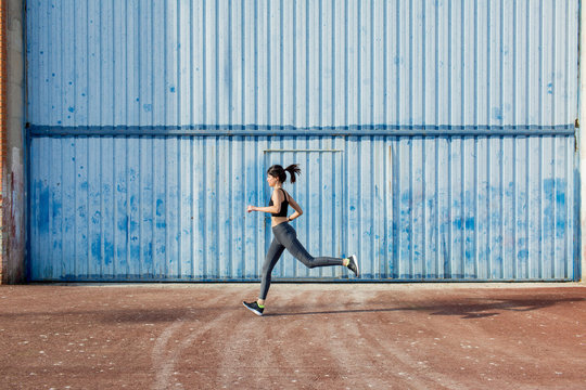 Young runner passing in front of a big blue metal door