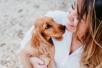 young woman and her cute puppy of cocker spaniel outdoors in a park