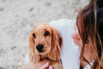 young woman and her cute puppy of cocker spaniel outdoors in a park