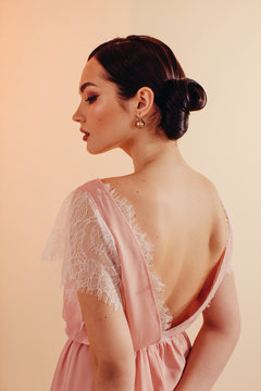 Back view portrait of young woman with bun hairstyle wearing stylish clothes