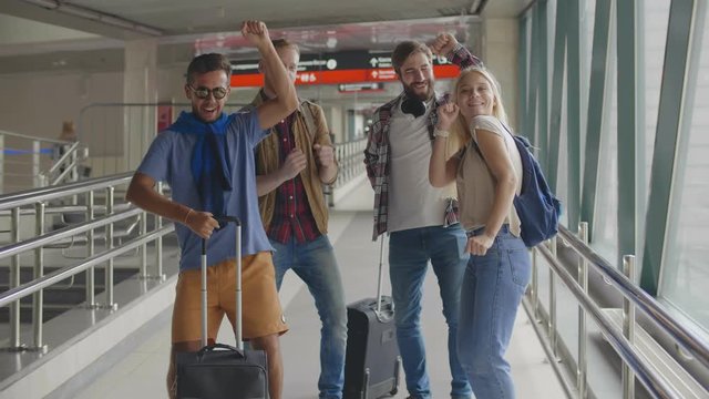 Portrait of optimistic young friends are funny dancing standing in terminal lounge.