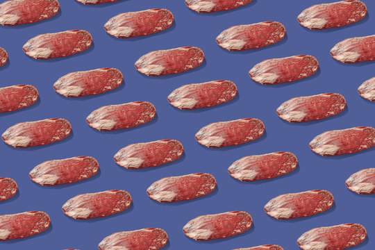 Creative pattern from raw natural organic meat fillet on a violet background with shadows. Flat lay