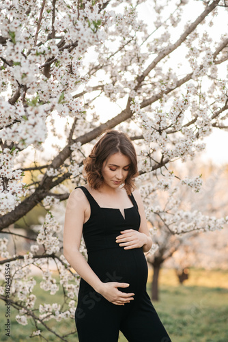 Sensual pregnant woman under blooming tree