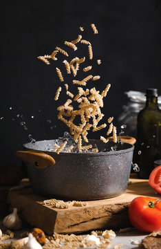 Homemade fusilli falling into saucepan