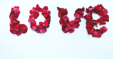 The word "love" is lined with red rose petals on a white background. Romance, simplicity, surprise 