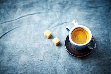 Cup of coffee and two brown sugar cubes on bright background. Copy space. 