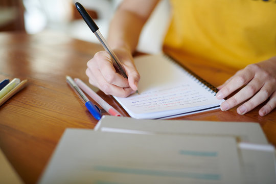 Crop girl writing in notepad doing studies