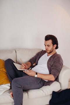 Young man writing in notebook indoors