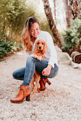 young woman and her cute puppy of cocker spaniel outdoors in a park