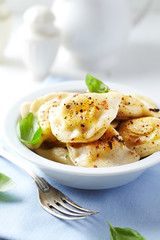 Dumplings with potato and cottage cheese stuffing (pierogi). Traditional Polish Christmas Dinner. Bright background. 