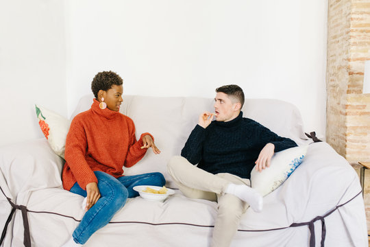 Friends eating chips on sofa