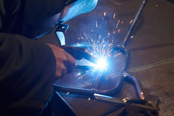 A man in a protective mask carries out welding work.