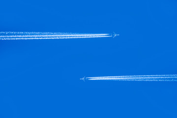 blue sky with condensation trail of two aircrafts passing each other