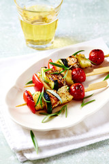 Shish Kebabs with fresh herbs on bright wooden background.