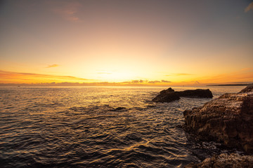 Sunrise over the sea. Rocks on the first plan