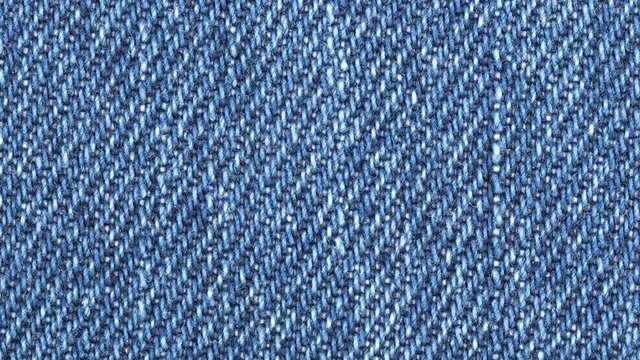 Jeans fabric plain surface background. Denim textile texture tracking. Top view. Slider shot. 4K 422 10 bit