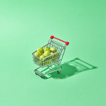 Shopping cart with brussels sprouts on a green background with reflection of shadows and a copy of space. Shopping