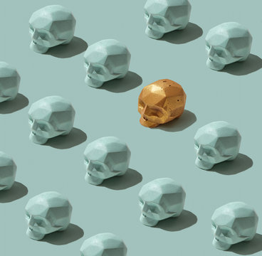 Set of gray skulls and one painted in golden skulls on a gray background . Creative background. Flat lay