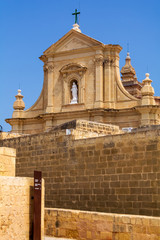 Obraz premium Facade of the Cathedral of the Assumption behind massive walls of the Cittadella of Victoria in Gozo, Malta. Cathedral is a fine baroque structure and is built entirely from local limestone.