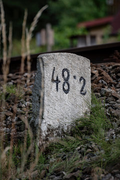 stone bollard with kilometers by railroad tracks