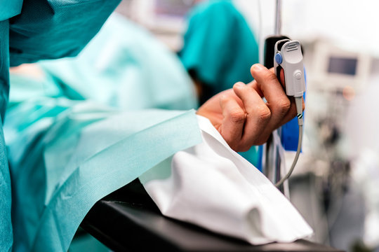 Patient lying in operating room with pulse oxymeter on finger
