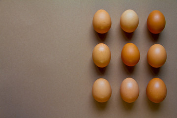 Nine brown chicken eggs on brown background, minimalistic food or easter concept