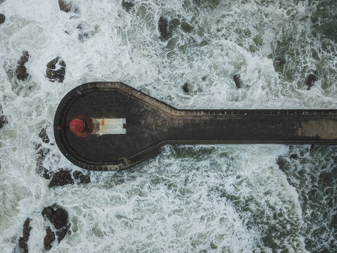 Drone view of lighthouse on pier in waves