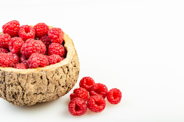 Lamponi rossi in ciotola di legno su sfondo bianco