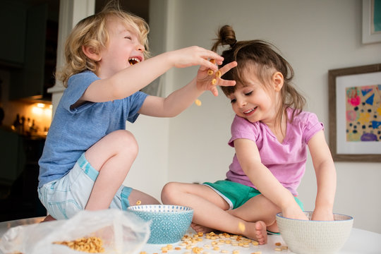 Kids Throwing Cereal On Top Of Table