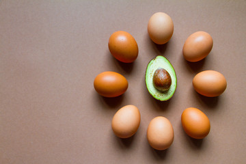 A few brown chicken eggs around a half of ripe avocado, the concept of ketogenic nutrition, the image of the watch dial