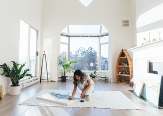 Female asian artist working on painting in minimalist studio