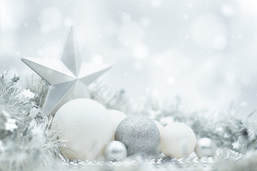 A festive design of silvery and white Christmas ornaments under a winter effect bokeh and snow...