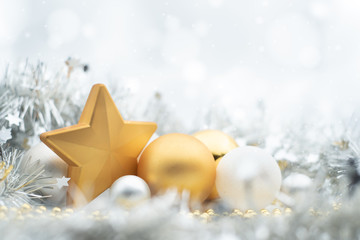 A design of festive gold and silver Christmas decorations under a wintry white bokeh background with copy space