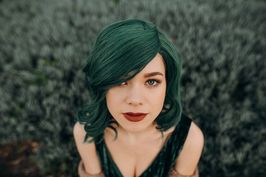 Portrait of young beautiful woman wearing a glamorous green costume wig and red lipstick