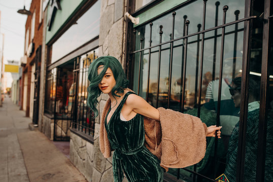 Young retro model hanging outside of a closed store leaning off of the bars on the sidewalk outside