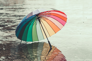 Rainbow umbrella on wet asphalt during cold weather in autumn rainy day in the fall. Rain protection