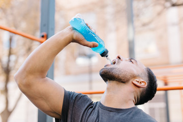 Young sportive man drinking from bottle